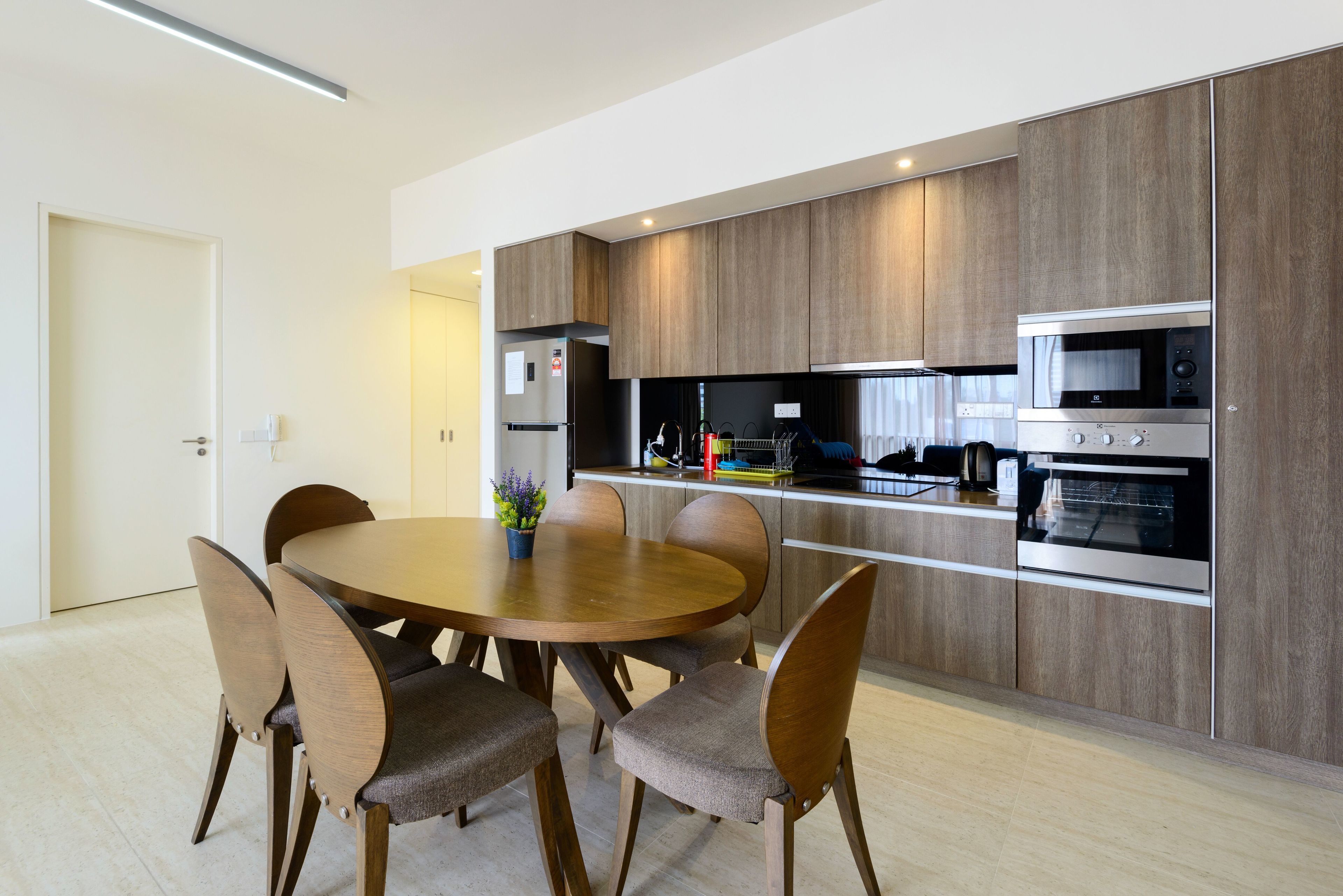 A modern kitchen with wooden cabinets, stainless steel appliances, and a round dining table with chairs.