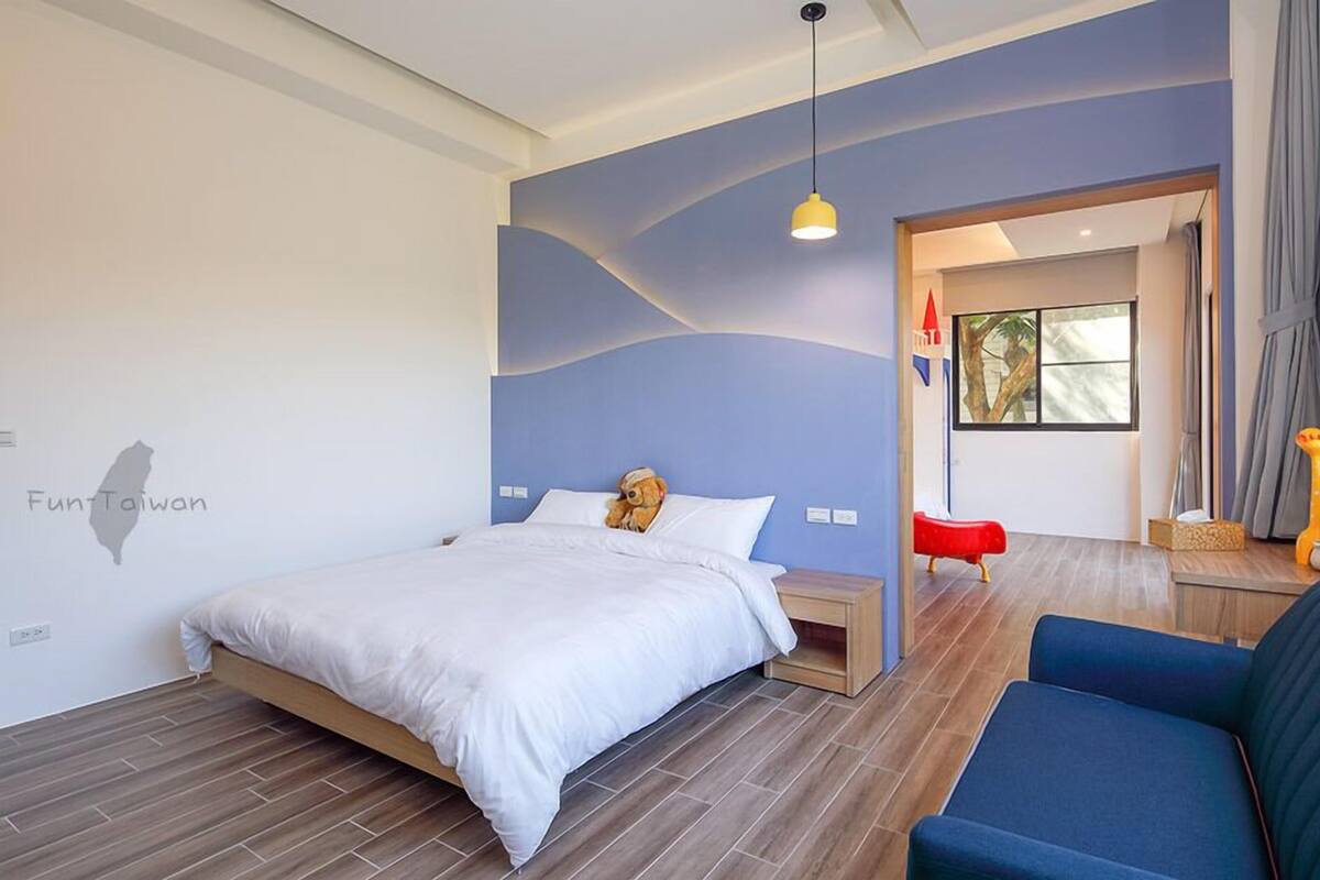 Una habitación de hotel moderna con una cama, un sofá azul, una silla roja y un mapa en la pared.