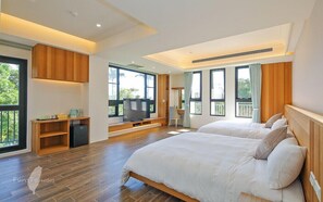 A modern bedroom with two beds, a TV, and a desk area.