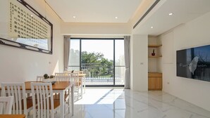A modern living room with a dining area, large windows, and a flat-screen TV. - Monet Garden B&B (Wujie)