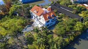 A large, multi-story house with a red-tiled roof, surrounded by lush greenery and a river. - Monet Garden B&B (Wujie)