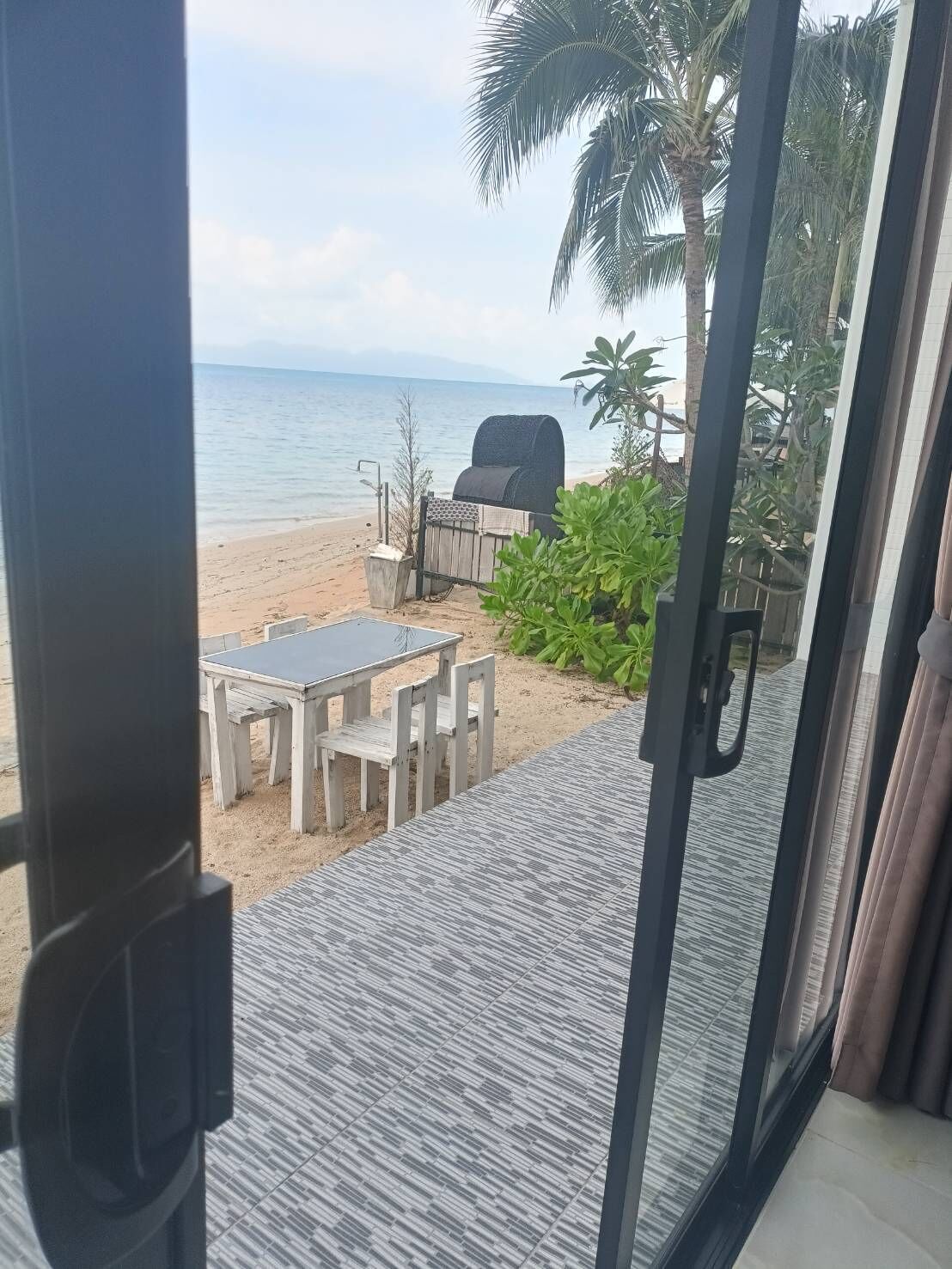Vista de una playa con una parrilla, una mesa y sillas.