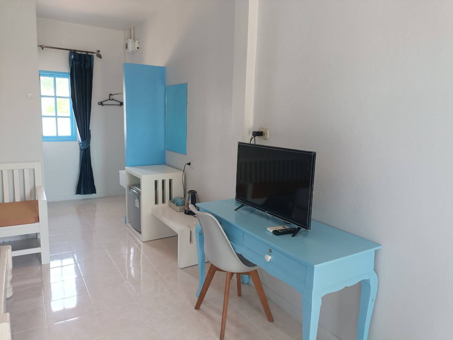 A modern room with a blue desk, a television, and a white chair.