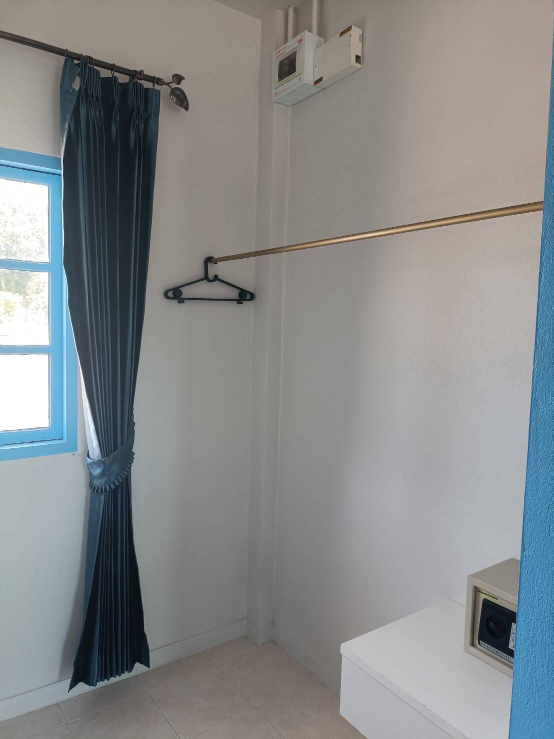 A bathroom with a shower, a towel rack, and a window with curtains.