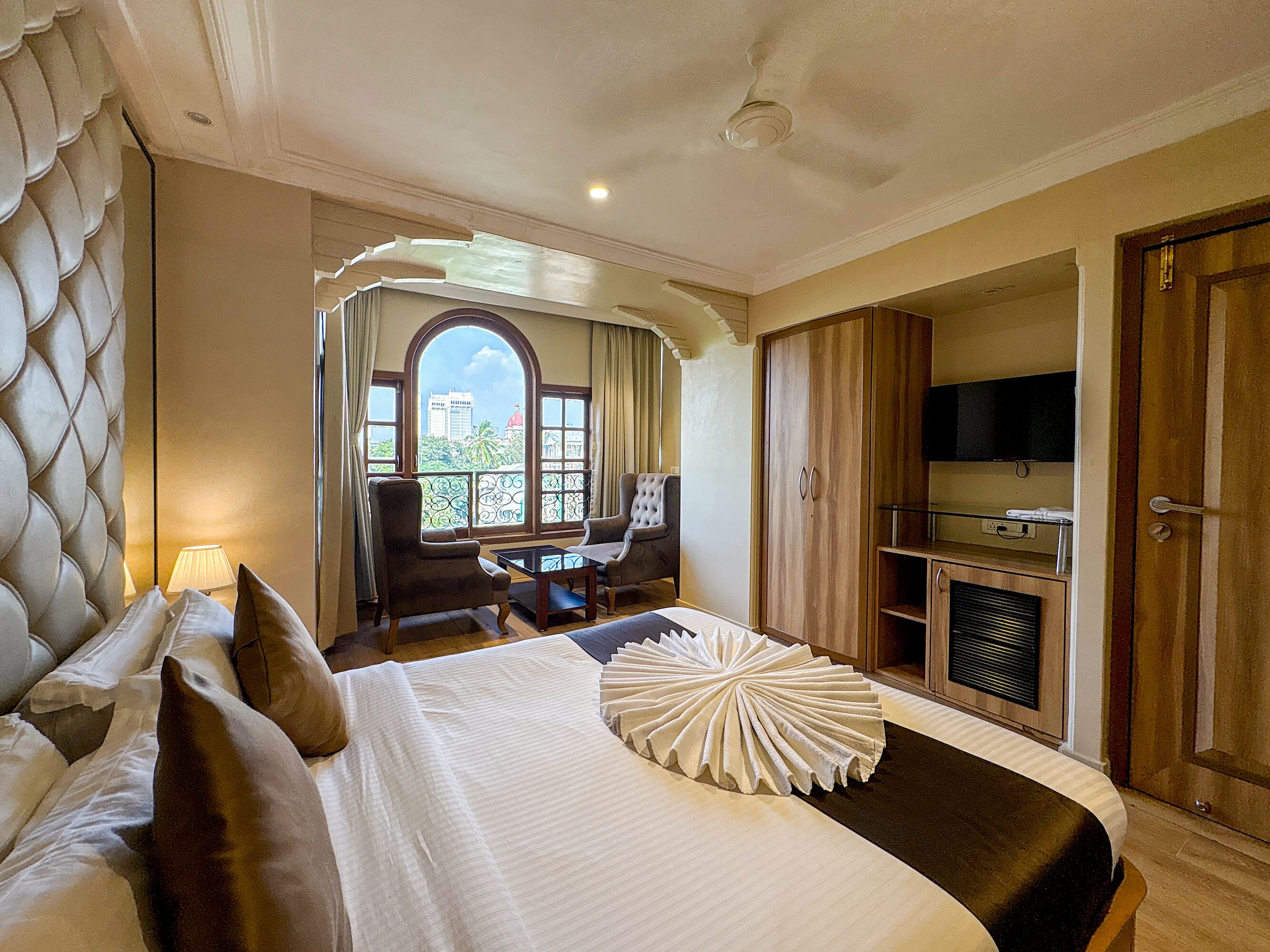 Habitación de hotel con cama, escritorio, silla, televisor y armario.