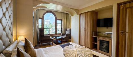 Habitación de hotel con cama, escritorio, silla, televisor y armario.