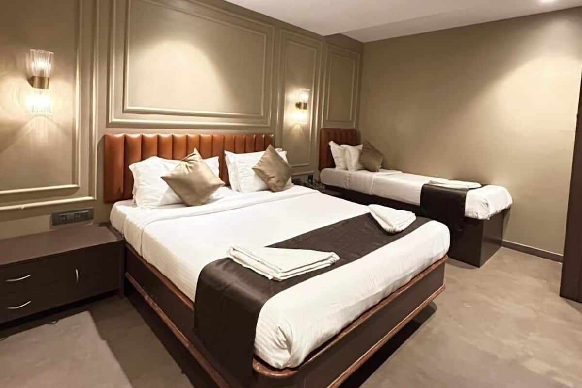A modern hotel room with a large bed, a smaller bed, and a seating area.