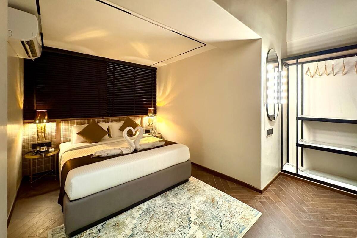 A modern bedroom with a large bed, bedside lamps, a nightstand, and a wardrobe with a mirror.