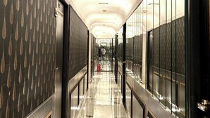 A corridor with reflective marble flooring, metallic doors, and a modern ceiling design. - Gulf Hotel Colaba (Mumbai)