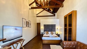 A hotel room with a bed, a TV, a sofa, a desk, and a wardrobe. - Gulf Hotel Colaba (Mumbai)