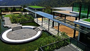 Un espace extérieur moderne doté d’un bassin circulaire, d’une terrasse en bois et d’espaces de détente clos par des parois de verre.