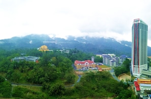 A high-rise building with a red vertical stripe, surrounded by lush greenery and other buildings. - OwnAstay Vista Suite Residences Genting (Genting Highlands)