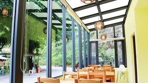 Un restaurante con amplios ventanales, mesas de madera y lámparas colgantes.