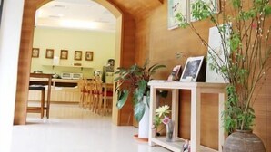 Un vestíbulo amplio con un mostrador de recepción de madera, plantas en macetas y obras de arte enmarcadas en las paredes.