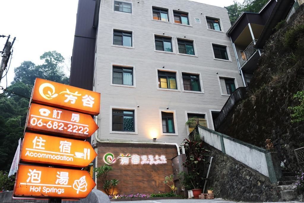 A multi-story building with a signboard indicating accommodation services, a contact number, and a logo.