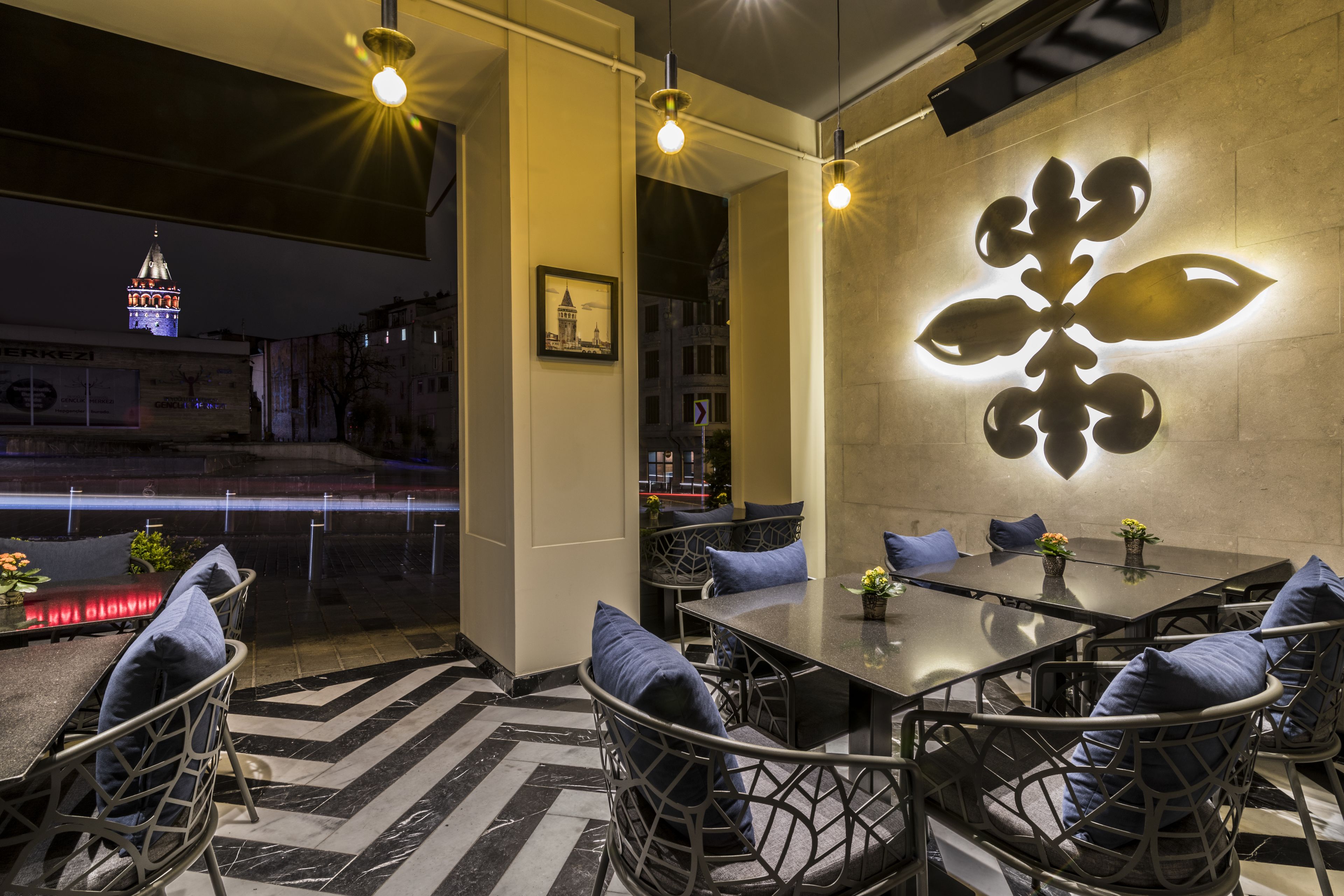 Un espace repas moderne avec une table en verre, des chaises en métal et un élément décoratif mural.