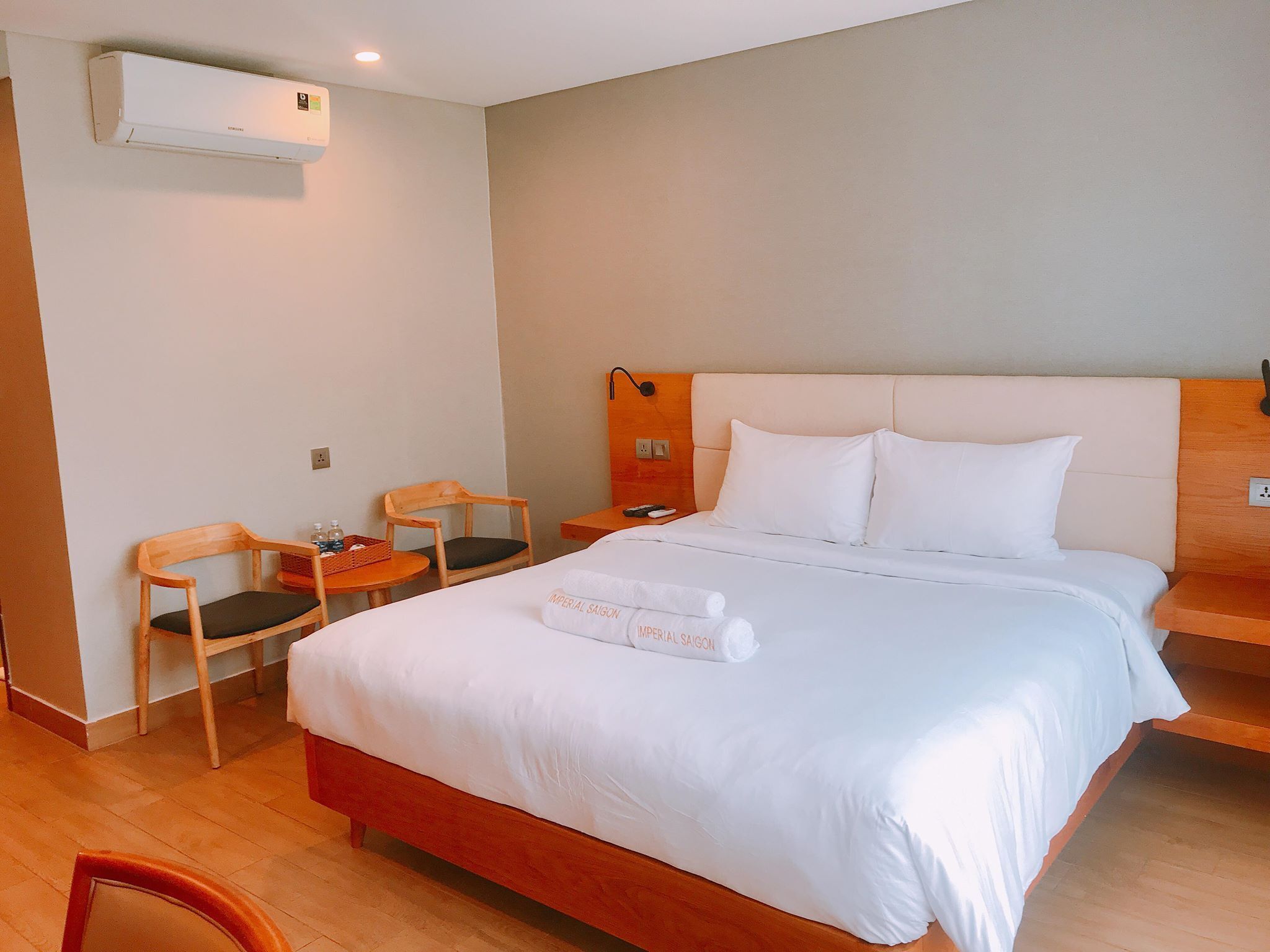 A hotel room with a bed, a wooden nightstand, a chair, and a small table.