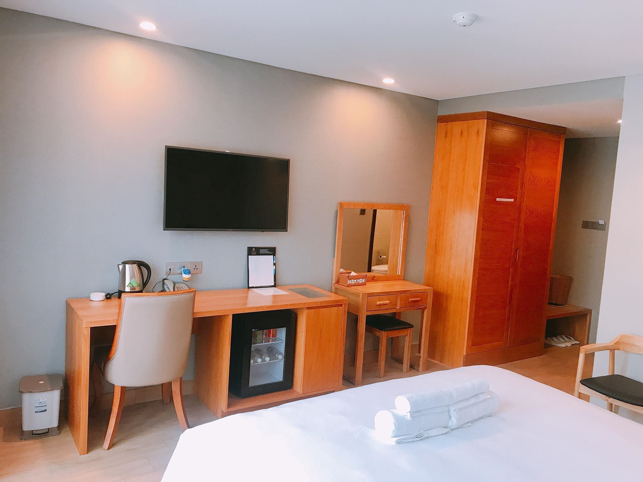 Une chambre d’hôtel comprenant un lit, un bureau avec une chaise, une télévision, une armoire et un petit meuble.