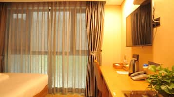 A hotel room with a bed, a desk with a telephone, a coffee maker, and a mirror.