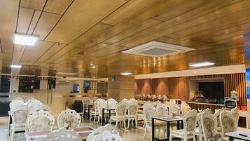 A hotel lobby with ornate white chairs and tables, a wooden ceiling, and a reception area with a counter and chairs.