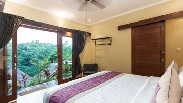 Un dormitorio con cama, ventilador de techo, ventana con cortinas, una silla y una puerta.