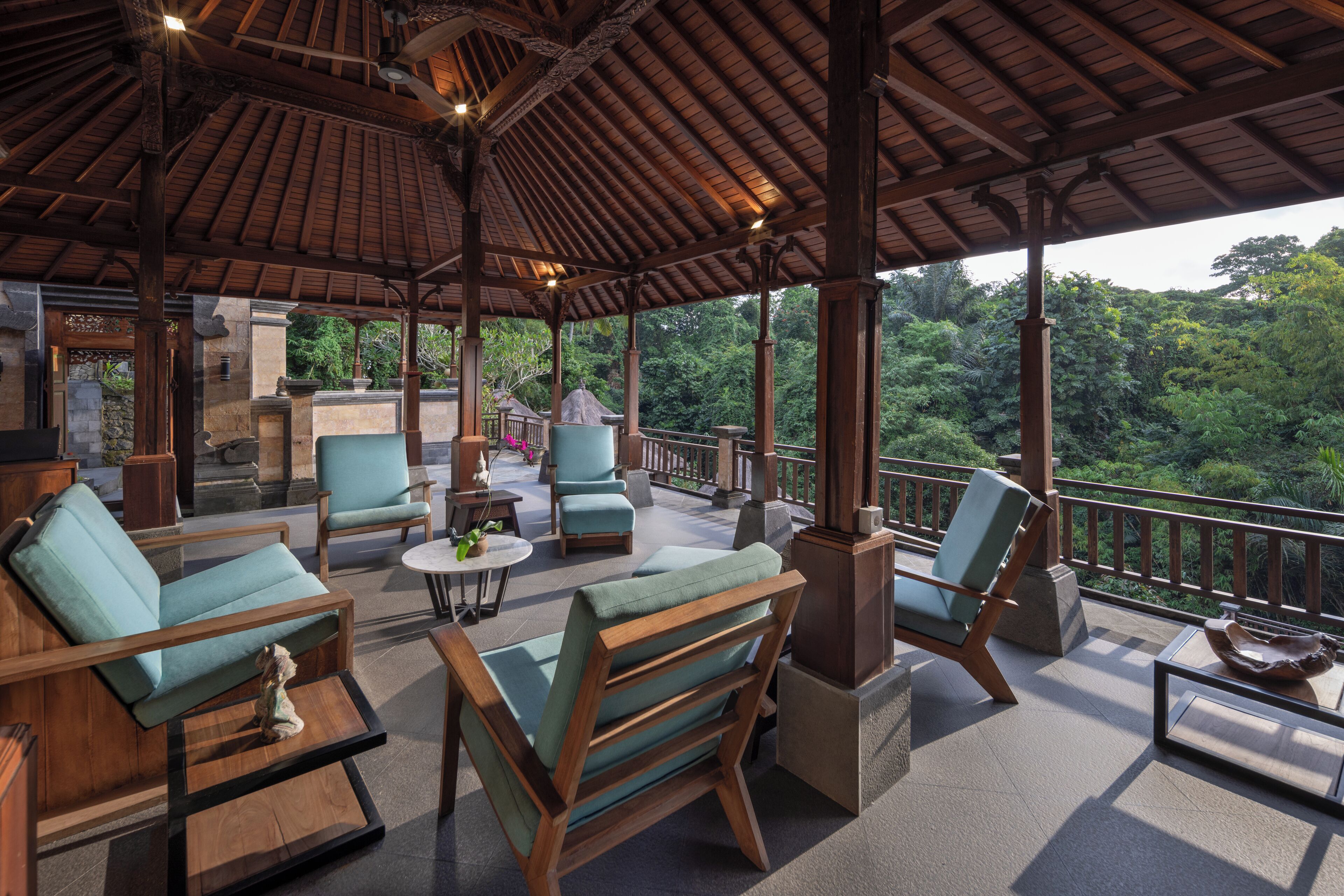 A covered outdoor area with wooden furniture and a view of the forest.