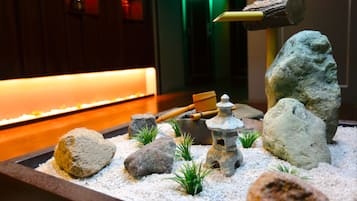 Jardín rocoso con rastrillo de madera, farol de piedra y plantas pequeñas.
