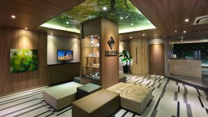 Eine moderne Lobby mit Holzboden, einem großen Fernseher, einer Rezeption und Sitzbereichen.