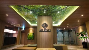 Eine Hotellobby mit einer zentralen Säule, einer Sitzecke und einer Decke im baumartigen Design.
