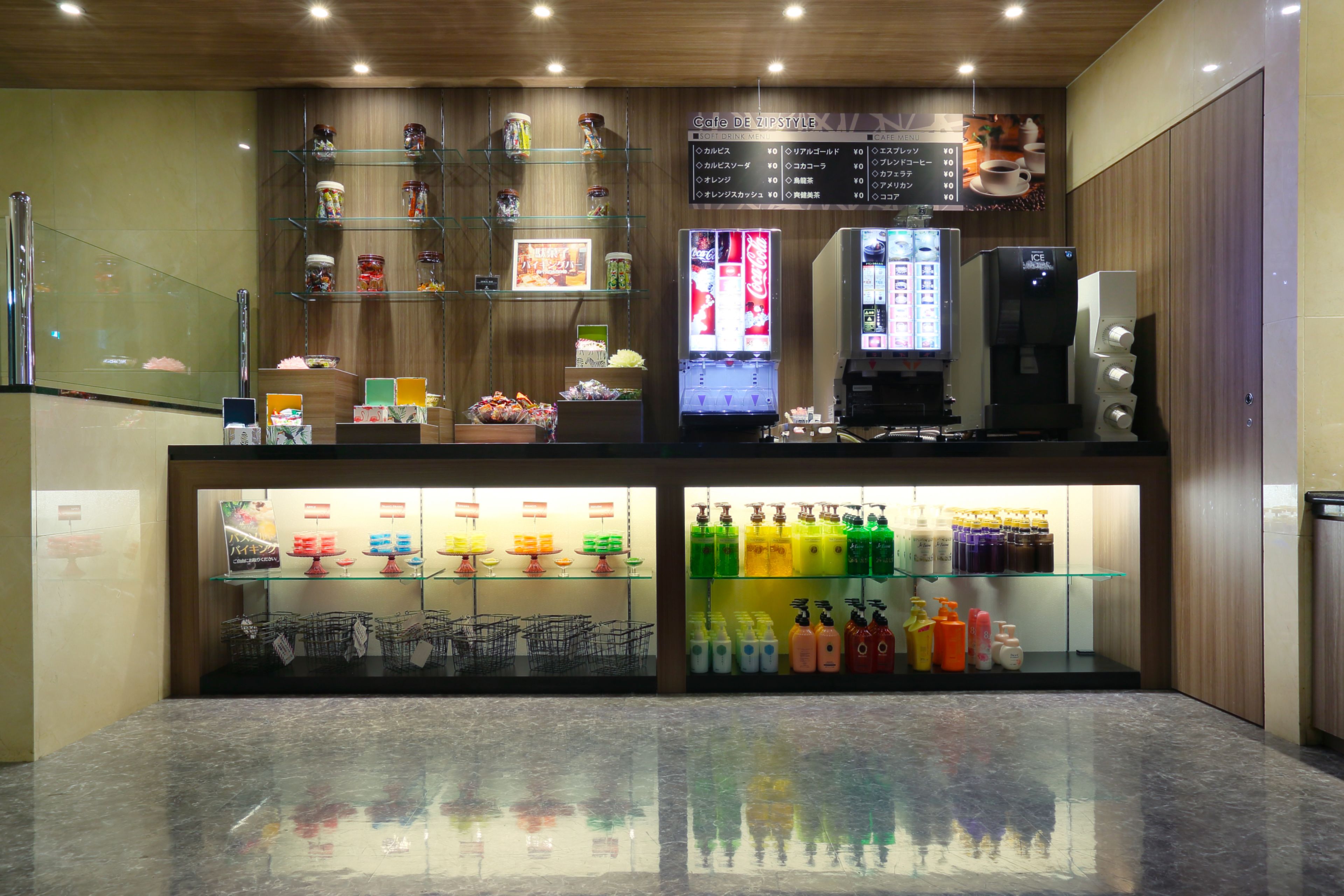 Una cafetería con interior de madera, un tablero de menú, máquinas expendedoras y estantes con diversos productos.