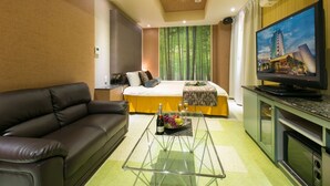 Ein modernes Hotelzimmer mit einer Couch, einem Bett mit Blick, einem Flachbildfernseher und einer kleinen Küchenzeile.