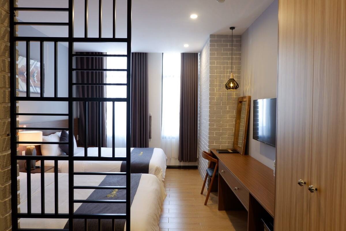 Una habitación de hotel moderna con cama, escritorio, televisión y un separador.