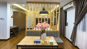 A hotel room with a wooden partition, a dining table with water bottles, snacks, and a tissue box. - The G.Hotel Hue - Hostel (Hue)