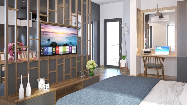 A modern bedroom with a large bed, a TV mounted on a wooden partition, and a desk with a computer. - The G.Hotel Hue - Hostel (Hue)
