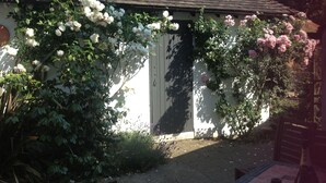 A building with a tiled roof, surrounded by white and pink flowering plants. - West End Lodge (Esher)