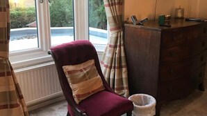 A room with a large window, a chair, a dresser, and a television. - West End Lodge (Esher)