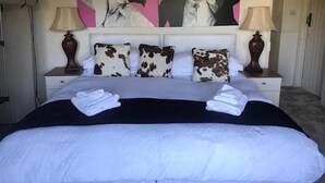 A neatly made bed with a black and white cover, two bedside lamps, and a pair of towels on the bed. - West End Lodge (Esher)