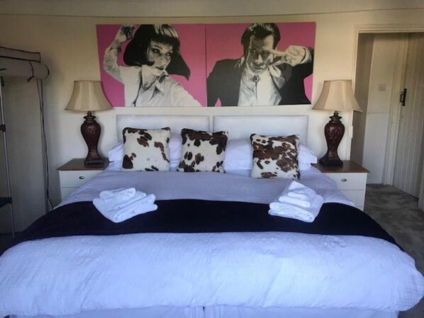 Un lit bien fait, recouvert d’une couverture noire et blanche, avec deux lampes de chevet et une paire de serviettes posées sur le lit.