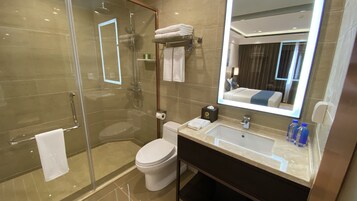 A modern bathroom with a glass-enclosed shower, a toilet, a sink with a mirror, and a towel rack.