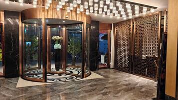 A lobby with a revolving door, a patterned floor, and a decorative wall with geometric patterns.