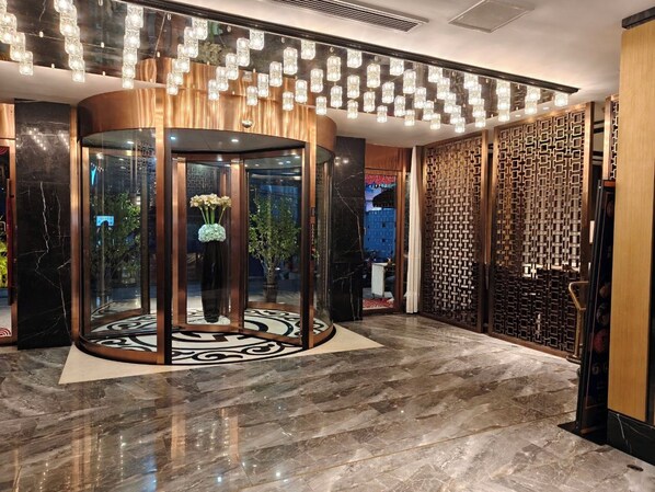 A lobby with a revolving door, a patterned floor, and a decorative wall with geometric patterns.