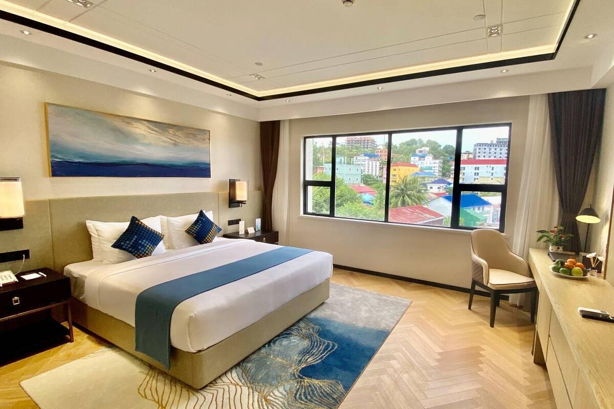 Una habitación de hotel moderna con una cama grande, un escritorio, una silla y un televisor.