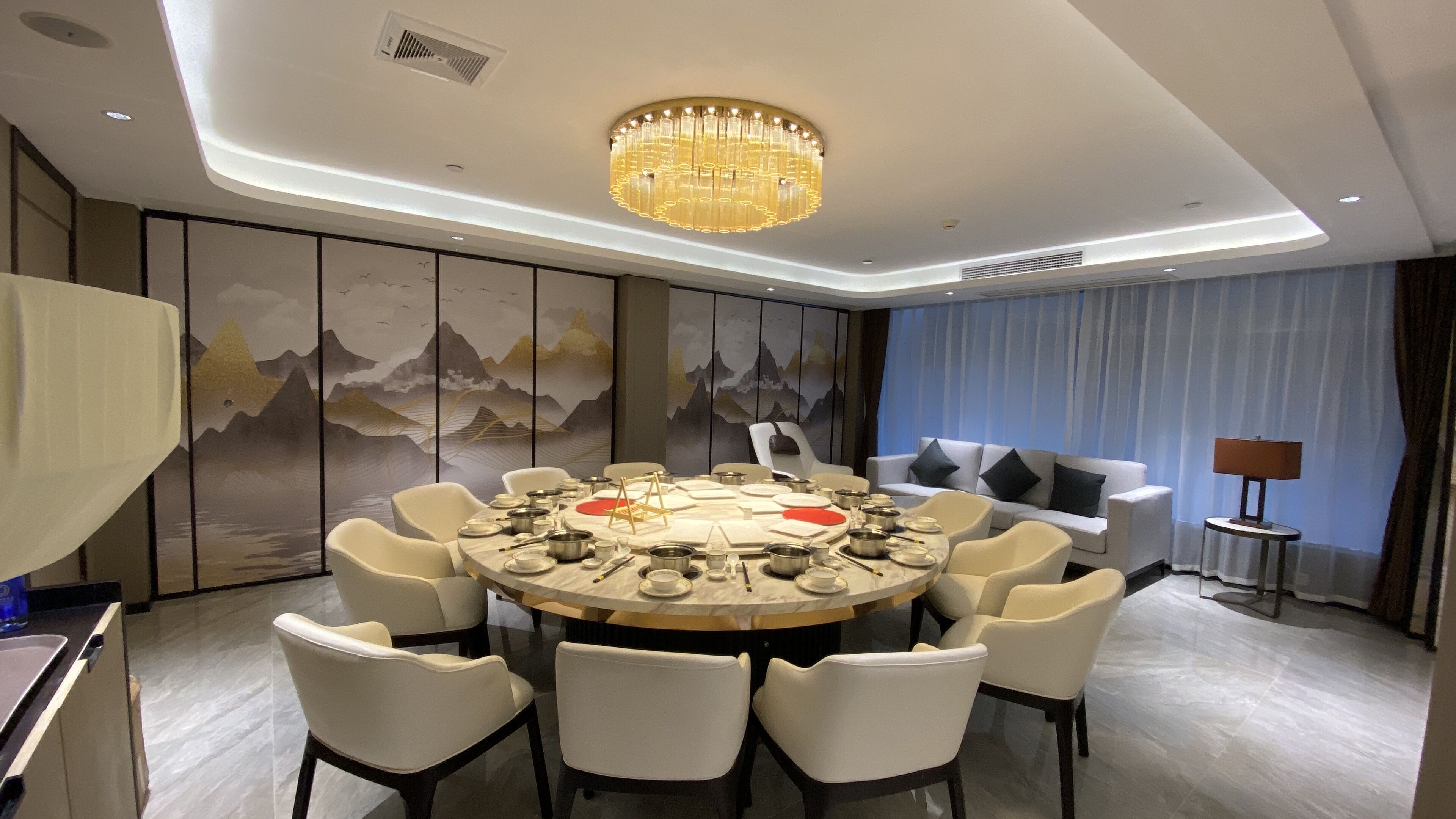 A modern dining room with a round table set for a meal, surrounded by chairs.