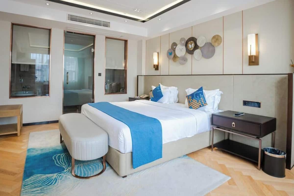 Una habitación de hotel moderna con una cama grande, mesita de noche y escritorio integrado.