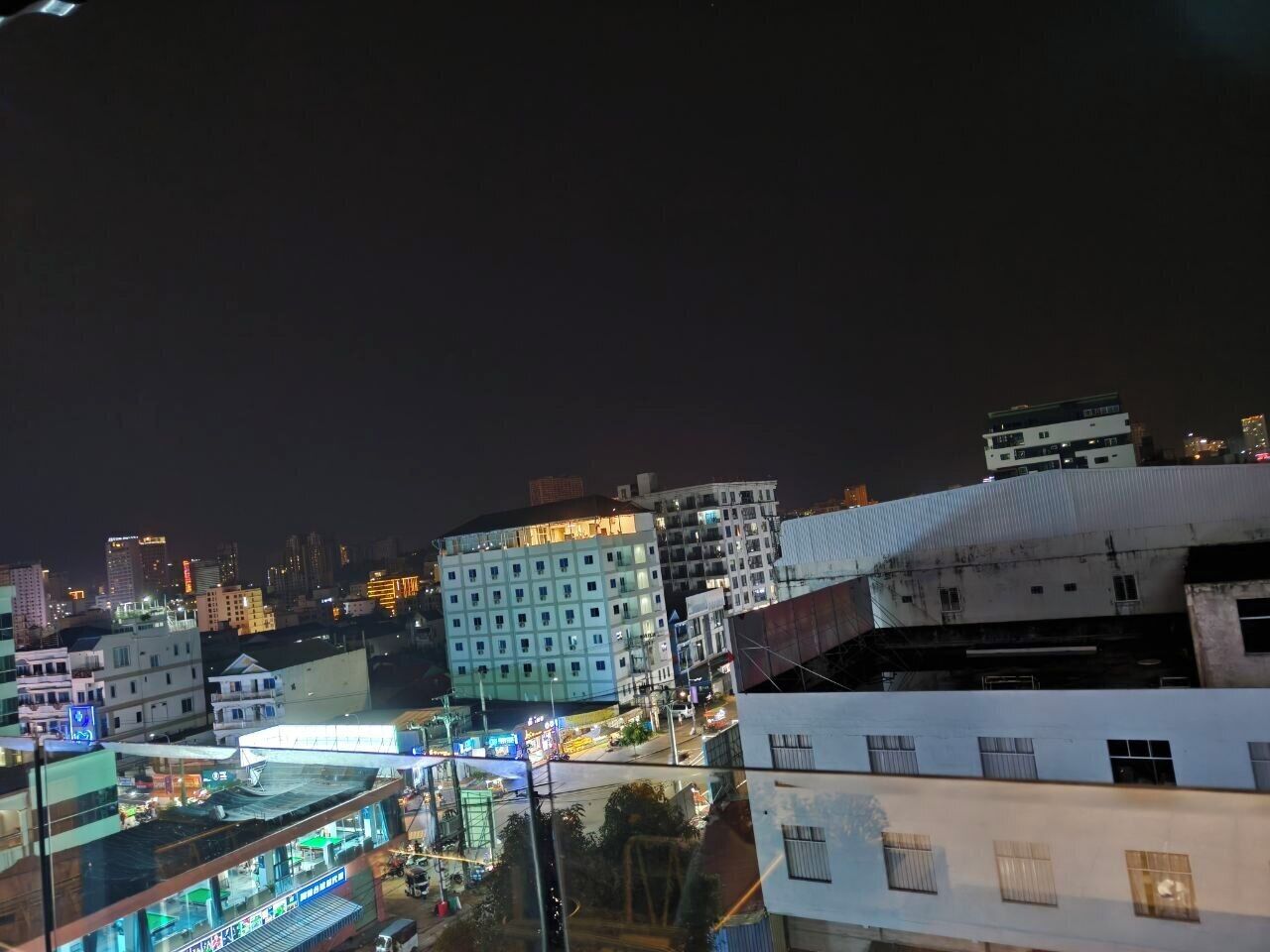 A nighttime cityscape with illuminated buildings and a view of a busy street below.