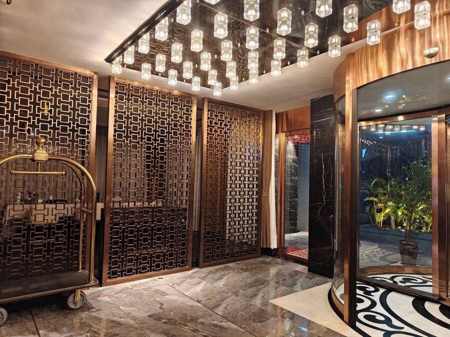 A modern interior with a patterned wall, a glass door leading outside, and a ceiling with multiple light fixtures.