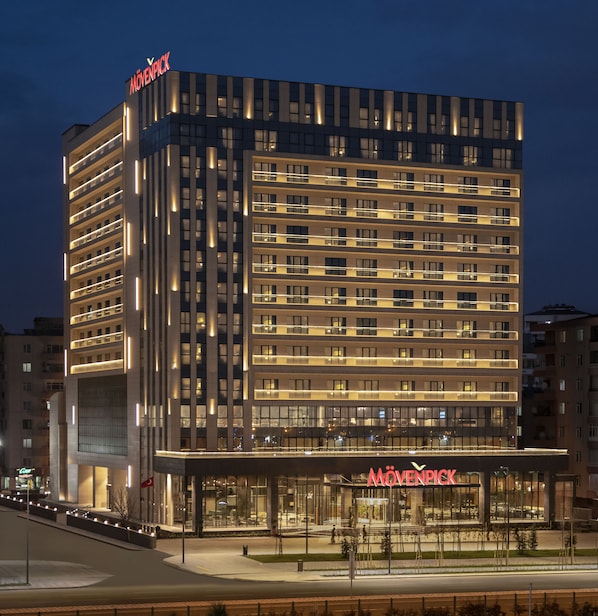 Un hotel moderno con un llamativo letrero de "Mövenpick", varios pisos y una fachada bien iluminada.