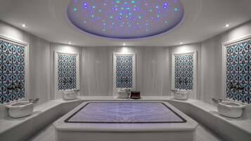 A modern bathroom with a large bathtub, two sinks, and a ceiling with blue LED lights.