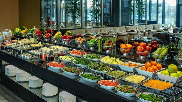 Ein reichhaltiges Buffet mit verschiedenen Speisen und Getränken, präsentiert auf einer Theke mit Tellern und Schüsseln.