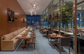 A modern restaurant with a long counter, booths, and a patterned floor. - Mövenpick Diyarbakir (Diyarbakir)